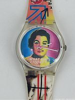 Close up of watch face showing pop art style segmented portrait of woman's face in four colors and text 'WHAT AM I TODAY'