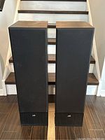 Front view of both tower speakers side by side, showing the fixed grills and overall condition