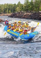 Group of rafters running whitewater rapids in a blue Wilderness Tours raft
