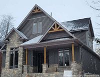 Two-story home with stone and siding exterior showing installed white eavestrough.