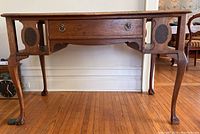 Full view of the antique wood desk showing the front design, claw feet, and side panel details.