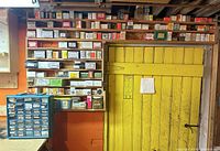 Wall storage and yellow door background with shelves filled with labeled fastener boxes.