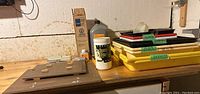 Photo showing Paterson film squeegee, chemical bottles including sodium sulfite powder, and various plastic developing trays stacked with size labels