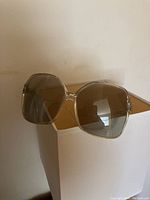 Close-up of large square translucent frame sunglasses with light brown lenses, showcasing vintage 1970s style
