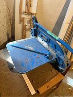 Blue metal shearer angled showing handle, base, and pivot arm with surface dirt and rust spots.