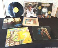 Seven vinyl records displayed, showing covers including Elton John and Eagles, and one record removed from cover