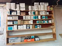 Full view of wooden shelf containing assorted fastener boxes arranged in compartments.