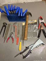Full view of tool lot items arranged flat on surface including hex keys, hammer, files, pliers, punch and screwdriver