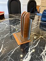 Photo showing front and side view of art deco bookend with layered copper and brass vertical panels on a square base.