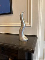 Front view showing the organic, wavy shape and polished aluminum finish.