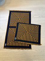 Two towels stacked, showcasing vintage YSL design in yellow and navy with fringes and embroidered logo.