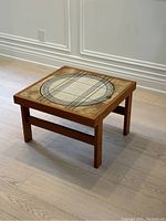 Full view of the teak and tile coffee table showing its square shape, tile surface with geometric pattern, and wood frame.
