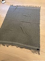 Full view of the striped merino wool blanket showing its size and twisted tassels along the edges.