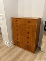 Front three-quarter view of six-drawer teak veneer dresser with circular recessed handles