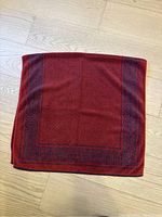 Full view of folded red and purple Yves Saint Laurent bath towel showing color and pattern details.