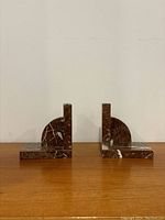 Front view of two red marble bookends showing half-circle vertical backs and rectangular bases.