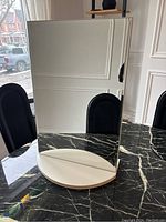 Front view showing the reflective surface of the mirror with a rectangular shape and white base.