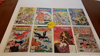 8 comics arranged on flat surface showing front covers. Titles include Marvel Star Comics Muppets Take Manhattan, Heathcliff, Get Along Gang, Prince Valiant, two Smurfs comics, Aladdin, New Kids on the Block. Smurfs comics show wear and rough condition.