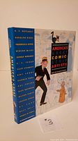 Front cover and spine of America’s Great Comic Strip Artists hardcover book with illustrated dust jacket and artist names on spine