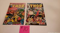 Lot of two Mighty Thor comic books #234 and #236 with a pink note labeled #70 in front, displayed on white surface.