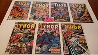 Seven The Mighty Thor Marvel comic books laid out in two rows, showing front covers with varied action scenes and characters.