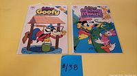 Two Disney Dynabrite comic books featuring Goofy and Mickey Mouse placed flat on a yellow background with a blue tag #138.
