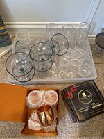 Overall view of acrylic stemware in plastic storage bin with boxed copper Moscow Mule cups beside it.
