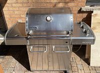 Front view of grill with closed lid showing side shelves and lower cabinet