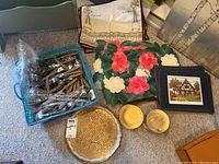 Basket with cutlery, napkin rings, placemats including floral velvet piece, coasters, Florentine tray, and a framed picture