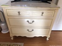 Front view of a painted wood dresser with three drawers and metal handles, showing wear on finish.