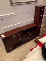 Three mini wooden filing cabinets of different sizes placed side by side against a wall, showing overall structure and finish