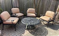 Four armchairs surrounding round metal coffee table on stone patio