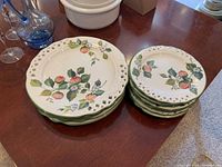 Photo showing stacked dinner and side plates with visible pierced edges and apple motif.