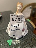 Close-up photo of the porcelain figurine with MaxSold tag 'Royal Doulton' visible on front