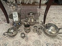 Photo of the entire silverplate set including coffee pot with warming stand, teapot, sugar bowl, creamer, salt and pepper shakers, and sterling silver salt cellar.