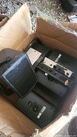 Box containing multiple black Tannoy D5 speakers and mounting brackets showing wear and used condition.