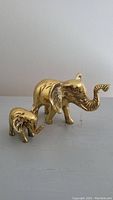 Side view photo of the larger and smaller brass elephant figurines placed on a flat surface.