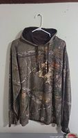 Front view of a Realtree camouflage hoodie, showing full garment with hood, drawstrings, and front pocket.