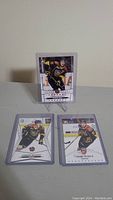 Three Connor McDavid rookie cards on a white surface, one displayed on a stand, showing front design with player in black/red jersey.