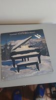Front album cover of Supertramp 'Even in the Quietest Moments' showing piano in snowy mountain scene