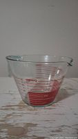 Front view of clear Pyrex measuring cup showing red measurement markings and pouring spout
