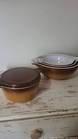 Three nested mixing bowls in brown to cream gradient pattern with white interiors