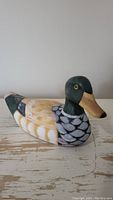 Side view of wooden duck decoy showing painted details on body, head and wings.