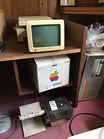 View of Apple 9 monitor on shelf with dot matrix printer below and storage box
