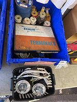 View of blue plastic container filled with multiple wire spools, a metal box labeled Echlin Terminals on top, and a small black basket below holding two round PIAA fog lights and wires.