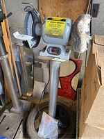 Full view of the bench grinder mounted on custom welded metal base, showing grinding wheel, buffing wheel, and power cord.