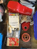 Photo of various small block Chevy SBC engine parts including a painted red steel oil pan, timing cover, water pump, valve covers, harmonic balancer, timing chain set box and bolt set.