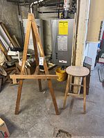 Full view of wood easel and stool in basement setting showing stand and stool details