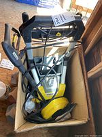 Karcher pressure washer unit and its spray gun and hose inside a box in a shed.