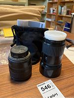 Photo showing two camera lenses side by side with Nikon lens pouch and a MaxSold tag.